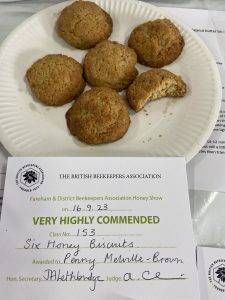 Plate of five round nubbly pale brown biscuits with the sixth having been nibbled and certificate. 