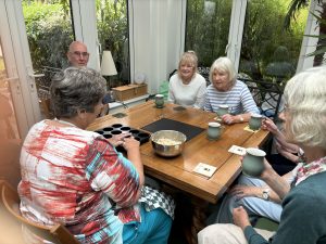 A group of seven visually impaired people sat with Penny around a table