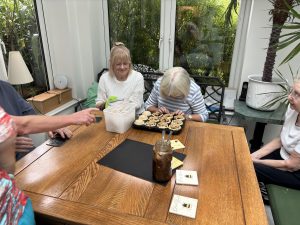 A visually impaired lady adding mincemeat and apple to a tray of pastry cases 