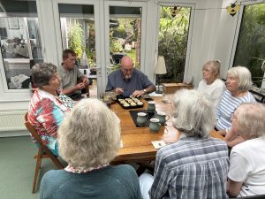 A group of visually impaired people sat around a table with one gentleman moulding pastry into a muffin tin