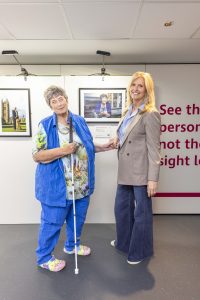 Penny is stood in front of her portrait holding hands with Penny Lancaster Stewart, who are both smiling to camera