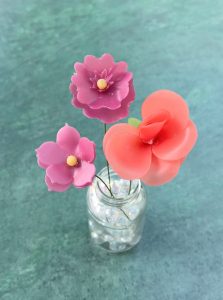 3 wax flowers made by Penny, in a vase.